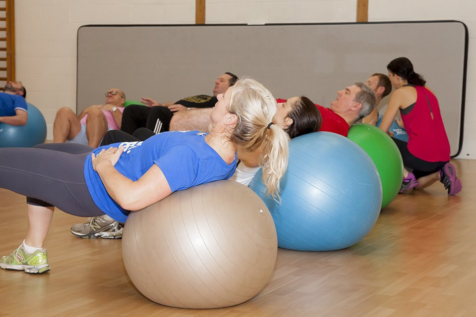 Patients lay back across large fitness balls in a class at St Andrews