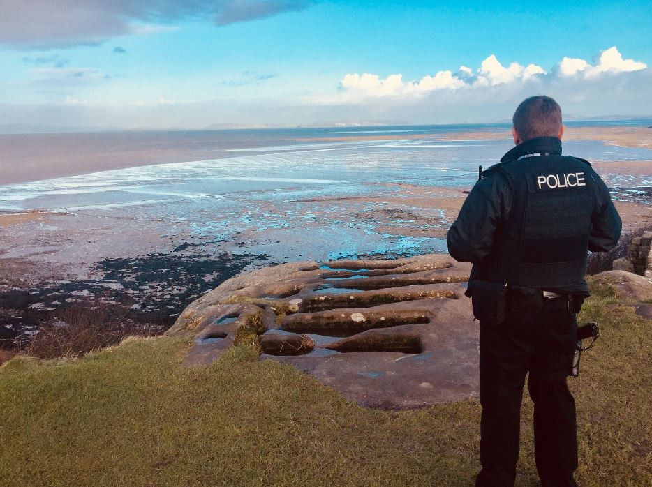 An officer looks out to sea with his back to the camera